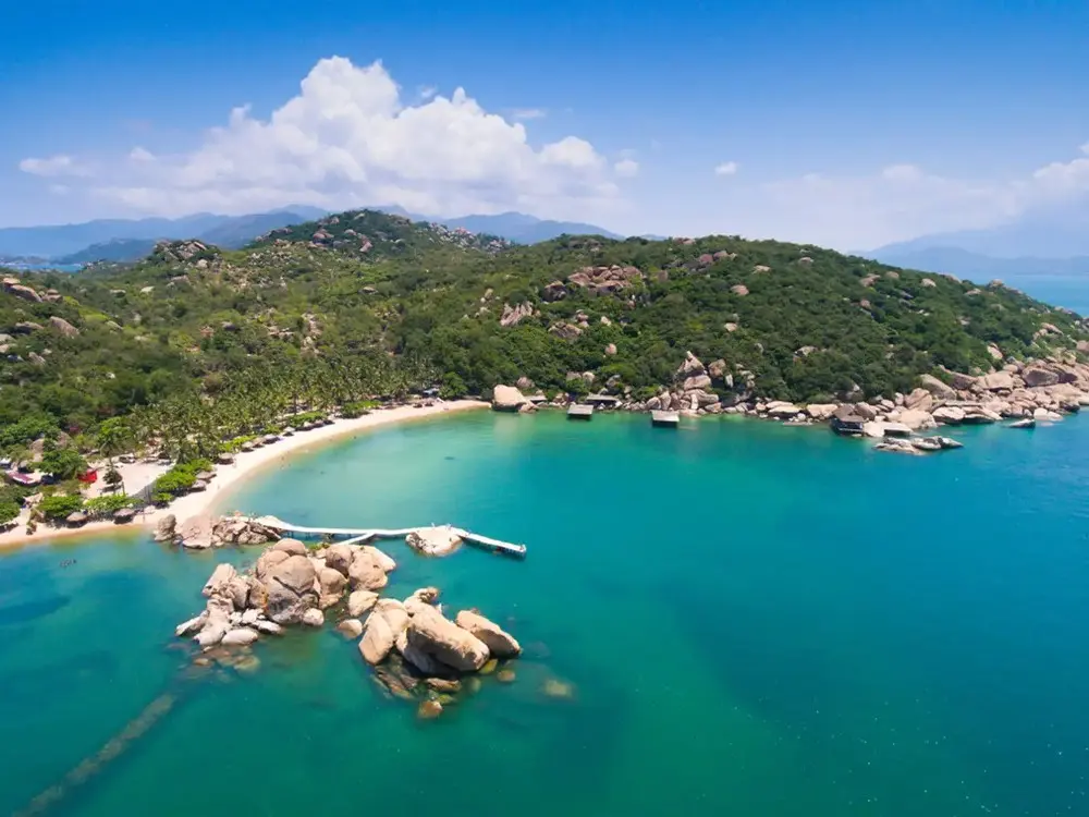 Scenic cove in Cam Ranh featuring a sandy beach, turquoise waters, and granite rock formations.