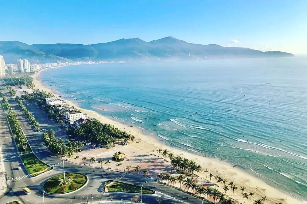 Overview of Da Nang sandy coastline with mountains in the background.