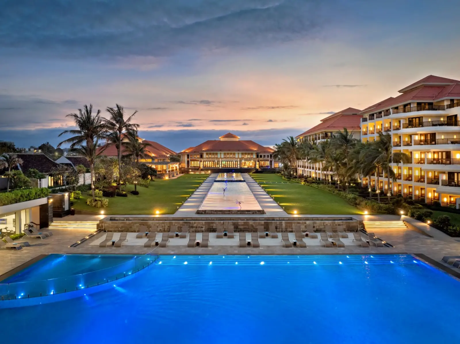 Вечерний вид на подсвеченный бассейн и главный корпус отеля Pullman Danang Beach Resort.