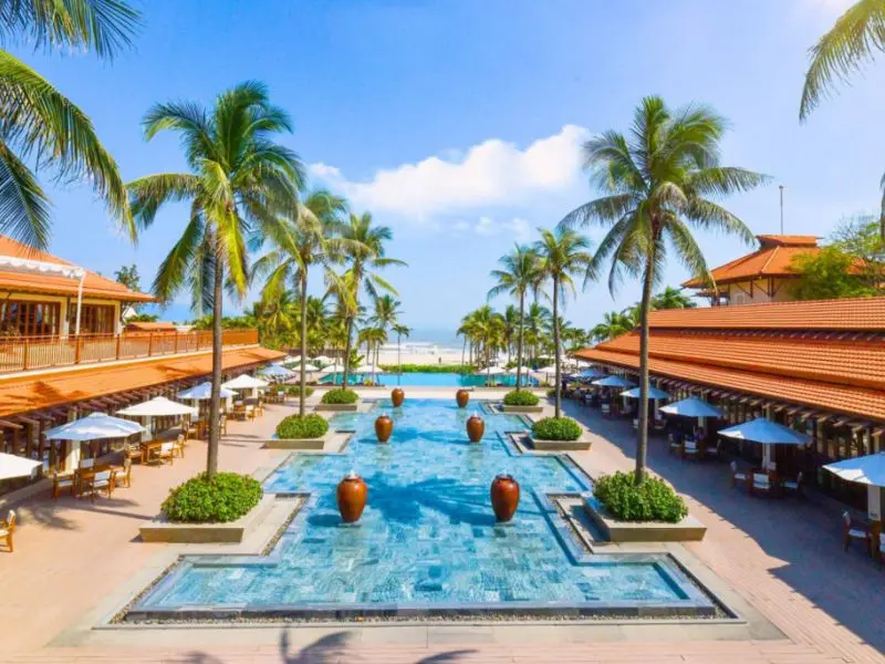 Внутренний двор отеля Furama Resort Danang с бассейнами, декоративными кувшинами и пальмами.