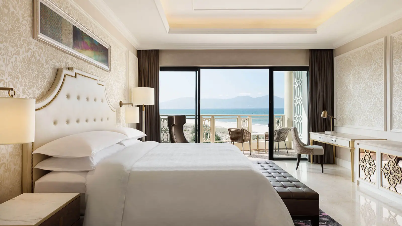 Светлый номер отеля с большой кроватью и балконом с видом на море.