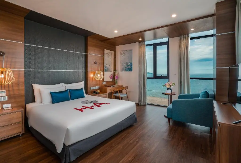 Bright hotel room with a large bed and panoramic ocean view window