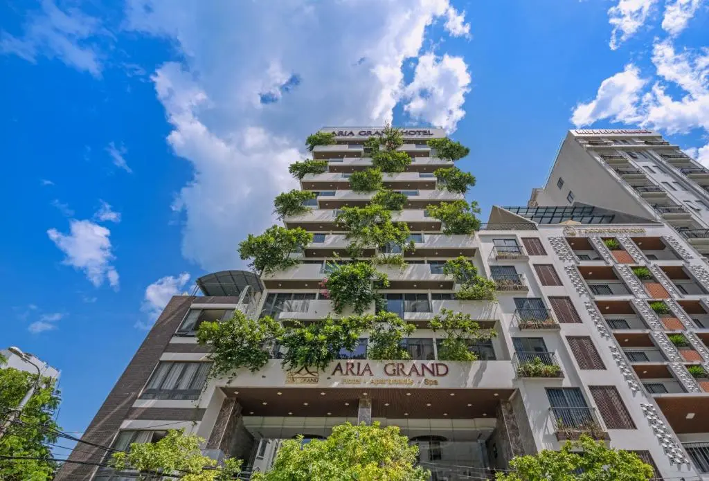 Фасад отеля Aria Grand Hotel & Spa с зелеными балконами на фоне синего неба