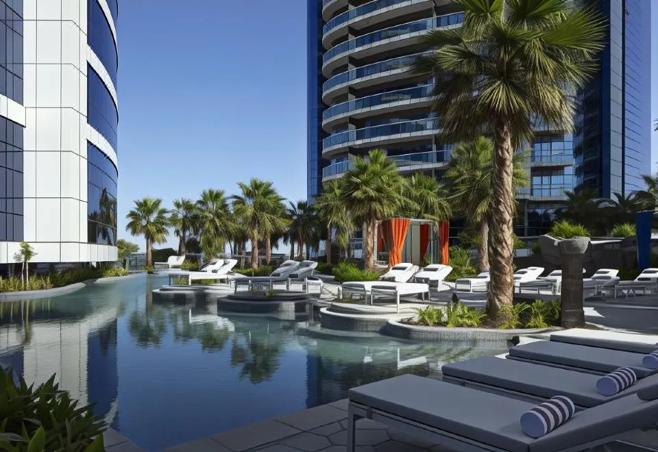 Outdoor swimming pool with sun loungers and palm trees at Paramount Hotel Dubai.