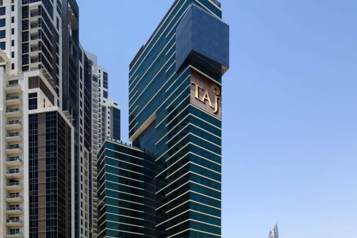 Современное высотное здание отеля Taj Dubai на фоне голубого неба
