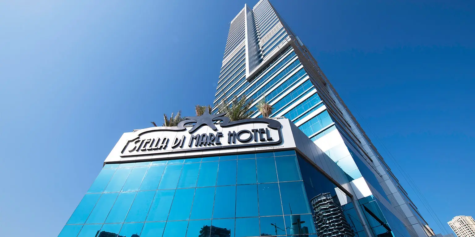 Modern exterior facade of Stella Di Mare Hotel in Dubai against a clear blue sky.