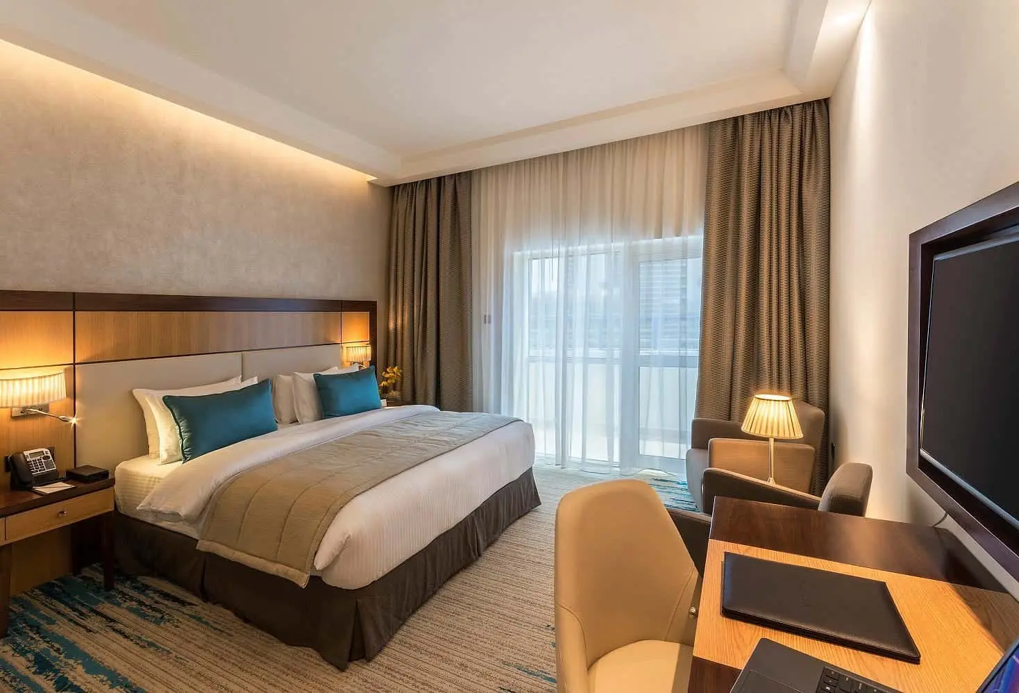 Cozy hotel room with a king bed, desk, and armchairs