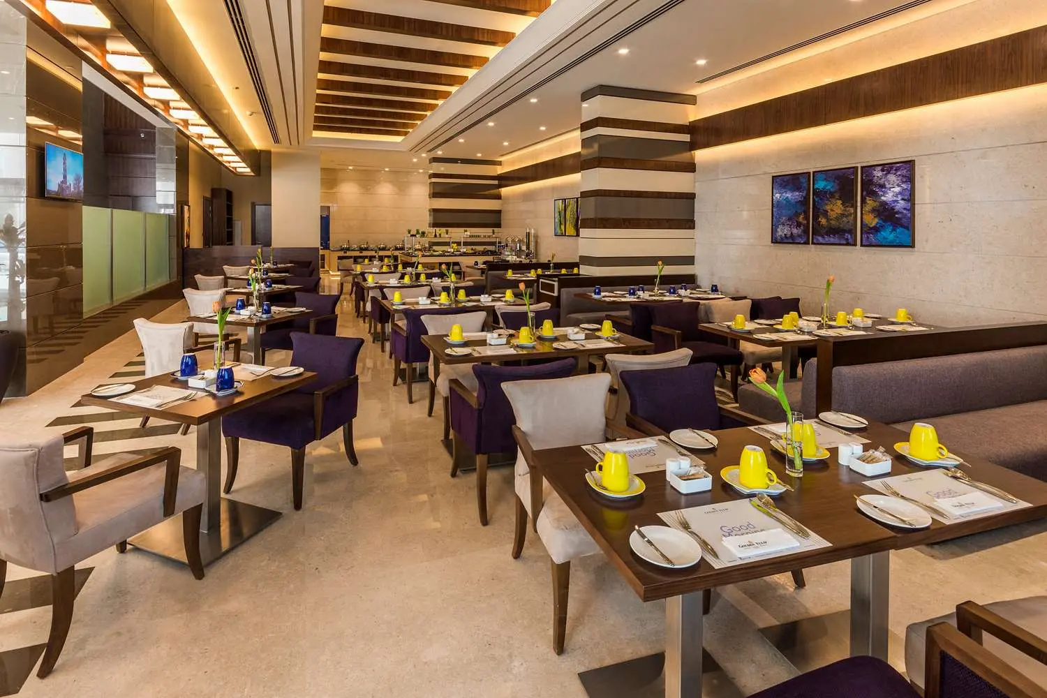 Hotel restaurant dining area with set tables and purple armchairs.