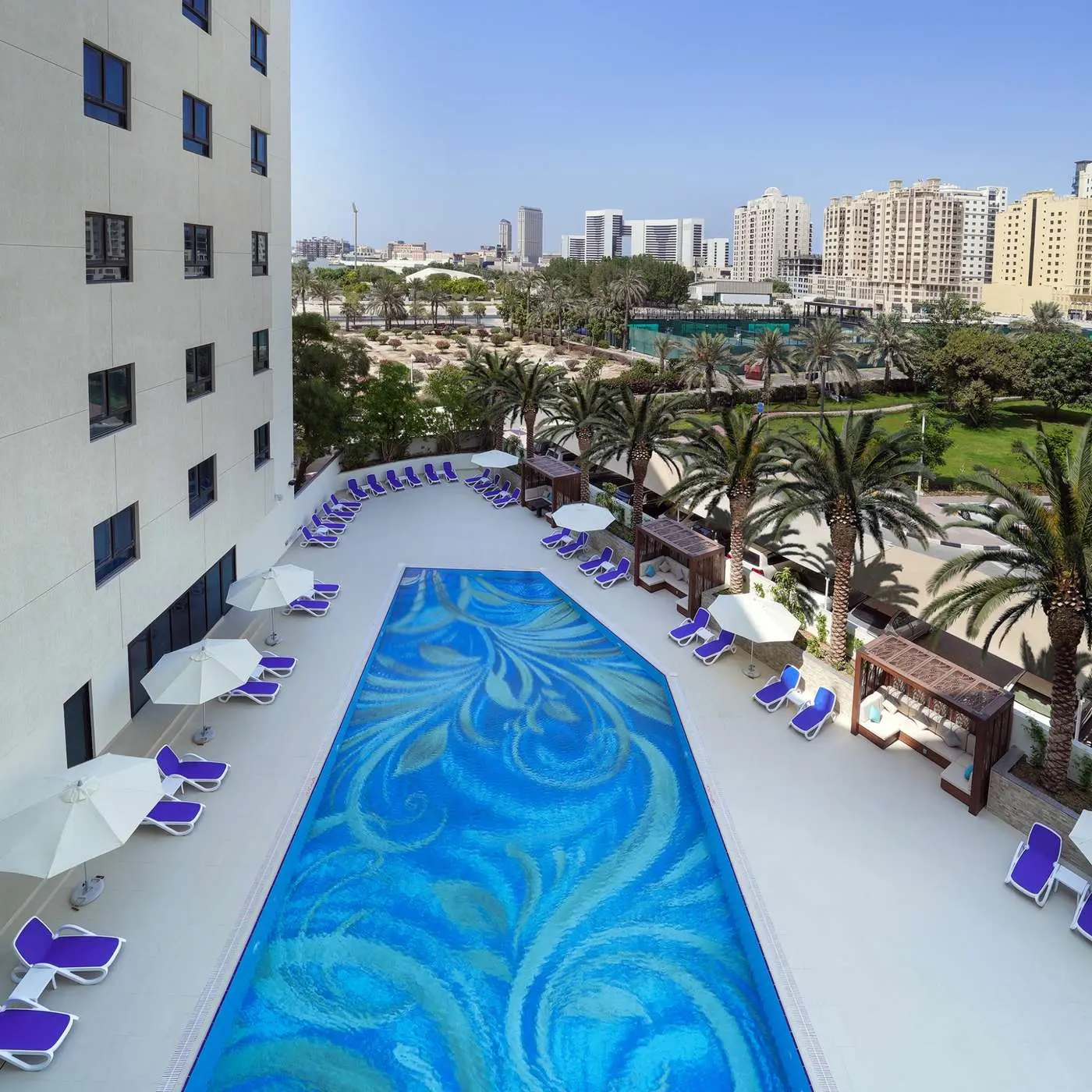 Aerial view of the hotel outdoor swimming pool with a mosaic pattern and lounge chairs.