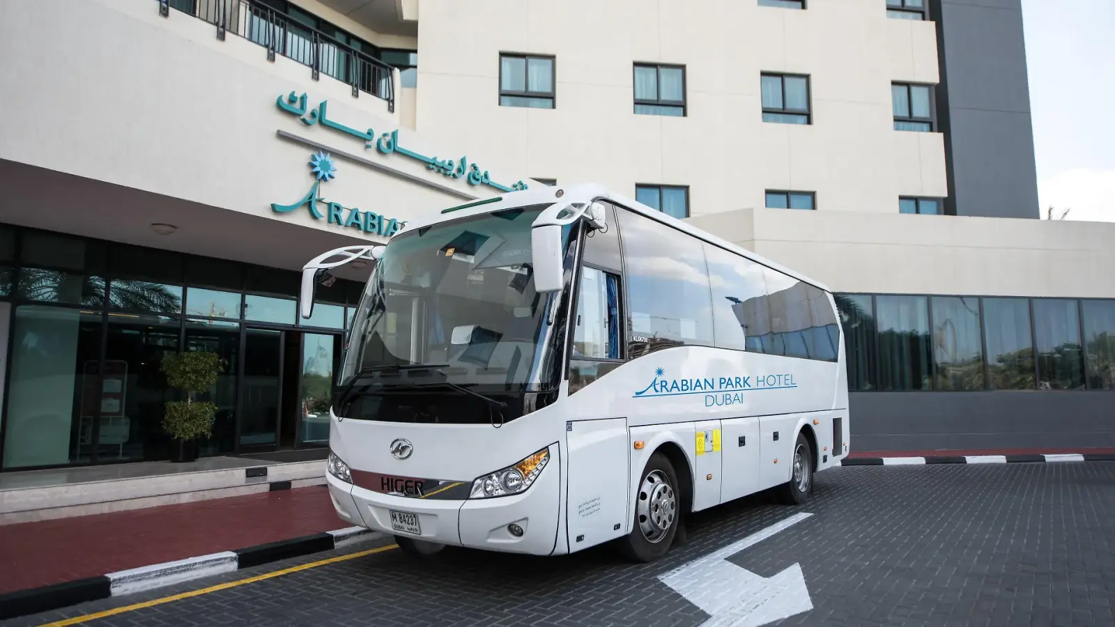 White Arabian Park hotel shuttle bus parked in front of the main entrance.