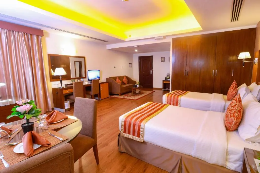 Spacious hotel room featuring twin beds and a dining area.